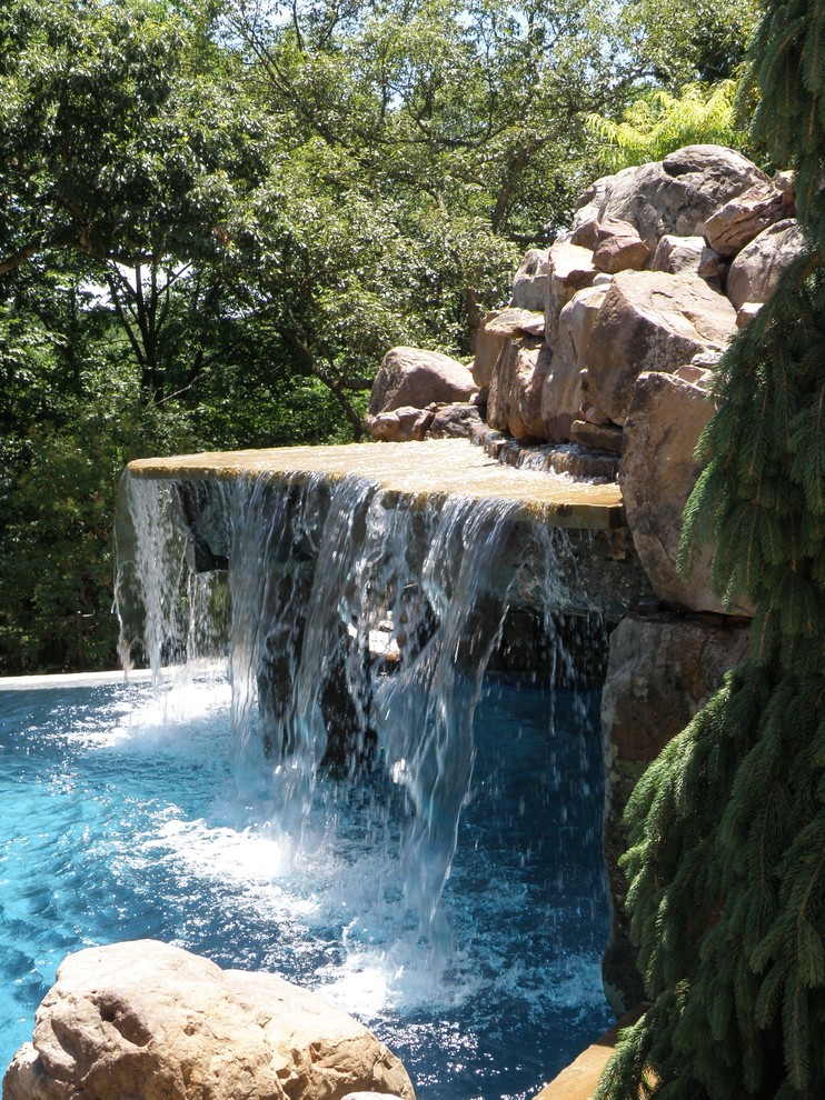 Foto på en mellanstor amerikansk pool på baksidan av huset, med en fontän