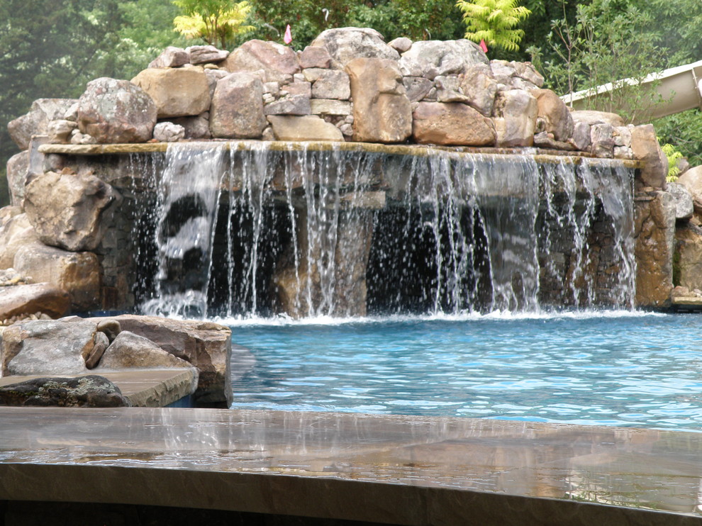 Immagine di una piscina american style personalizzata di medie dimensioni e dietro casa con fontane