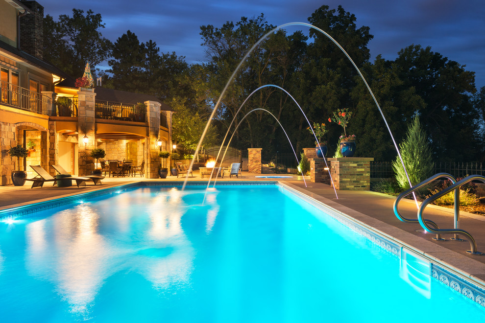 Modelo de piscinas y jacuzzis alargados mediterráneos grandes rectangulares en patio trasero con adoquines de hormigón