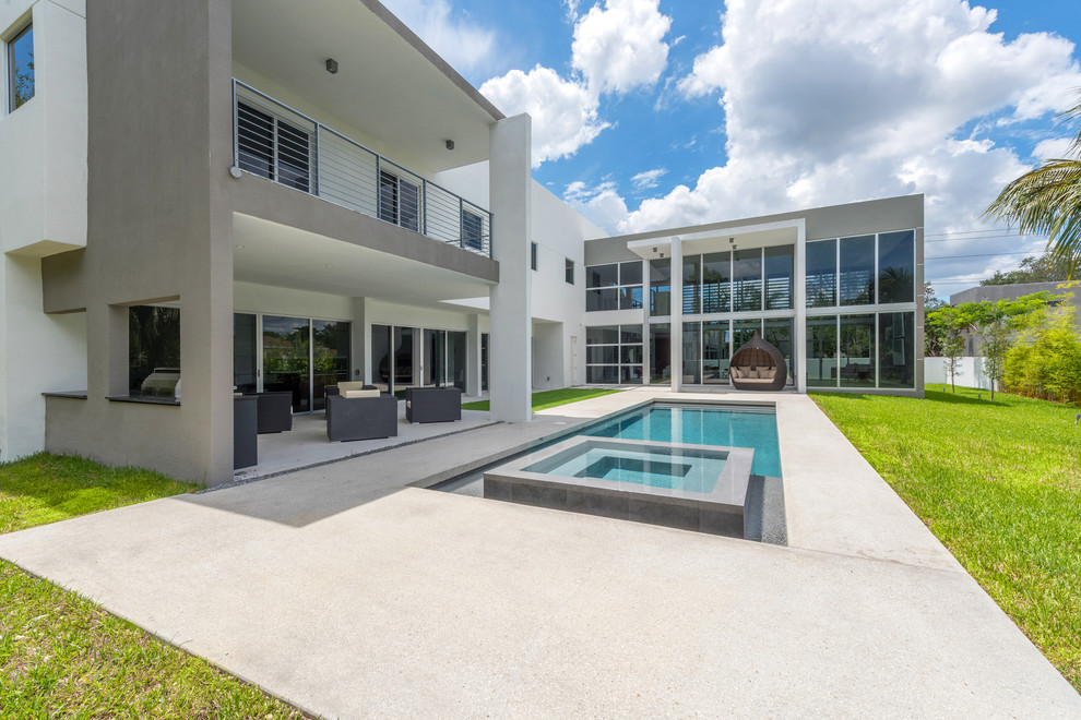 Ejemplo de piscinas y jacuzzis infinitos minimalistas de tamaño medio rectangulares en patio trasero con losas de hormigón