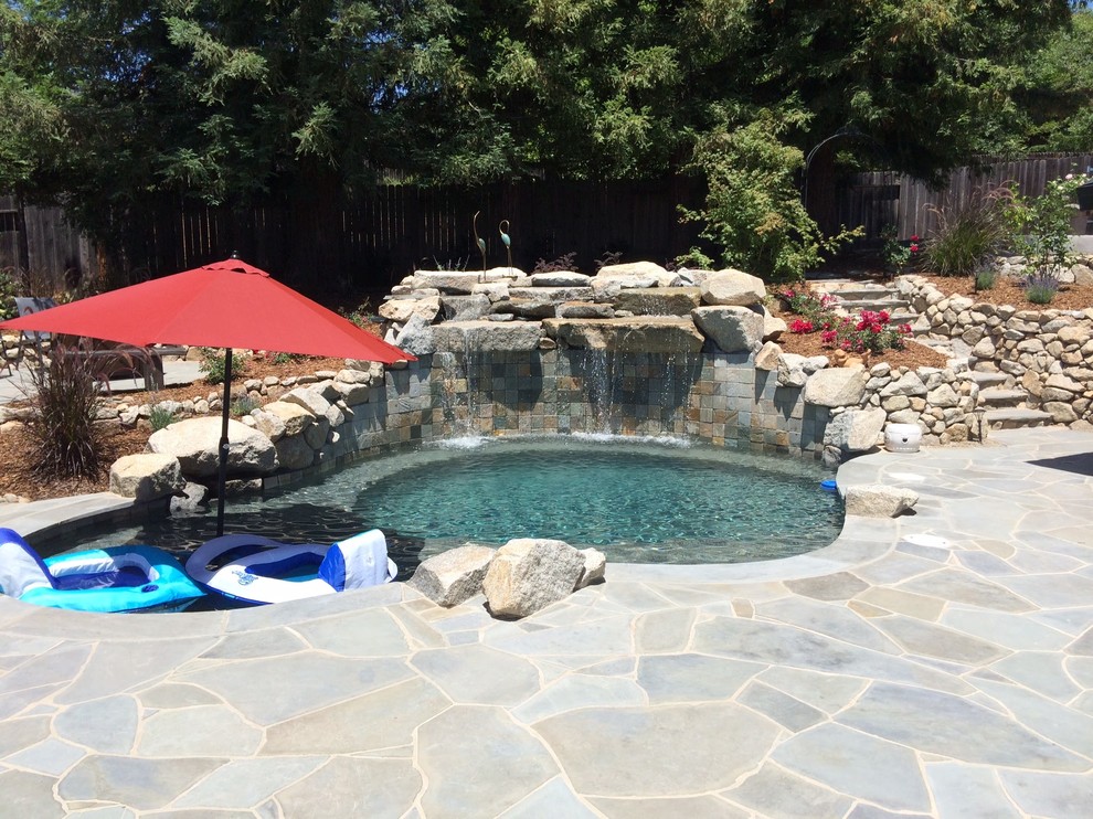 Diseño de piscinas y jacuzzis naturales clásicos de tamaño medio a medida en patio trasero con adoquines de piedra natural