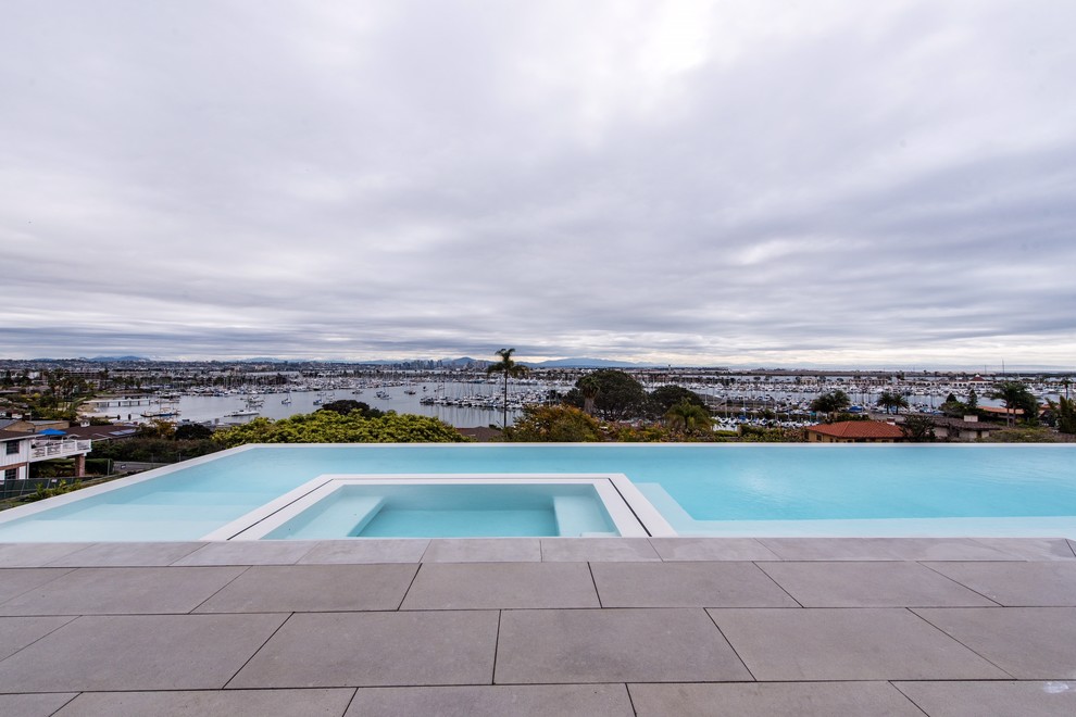 Inspiration for a large contemporary backyard concrete paver and rectangular infinity pool remodel in San Diego