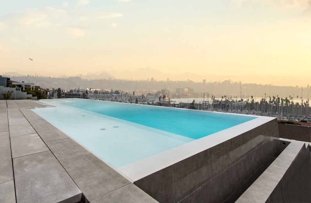Esempio di una grande piscina a sfioro infinito minimal rettangolare dietro casa con pavimentazioni in cemento