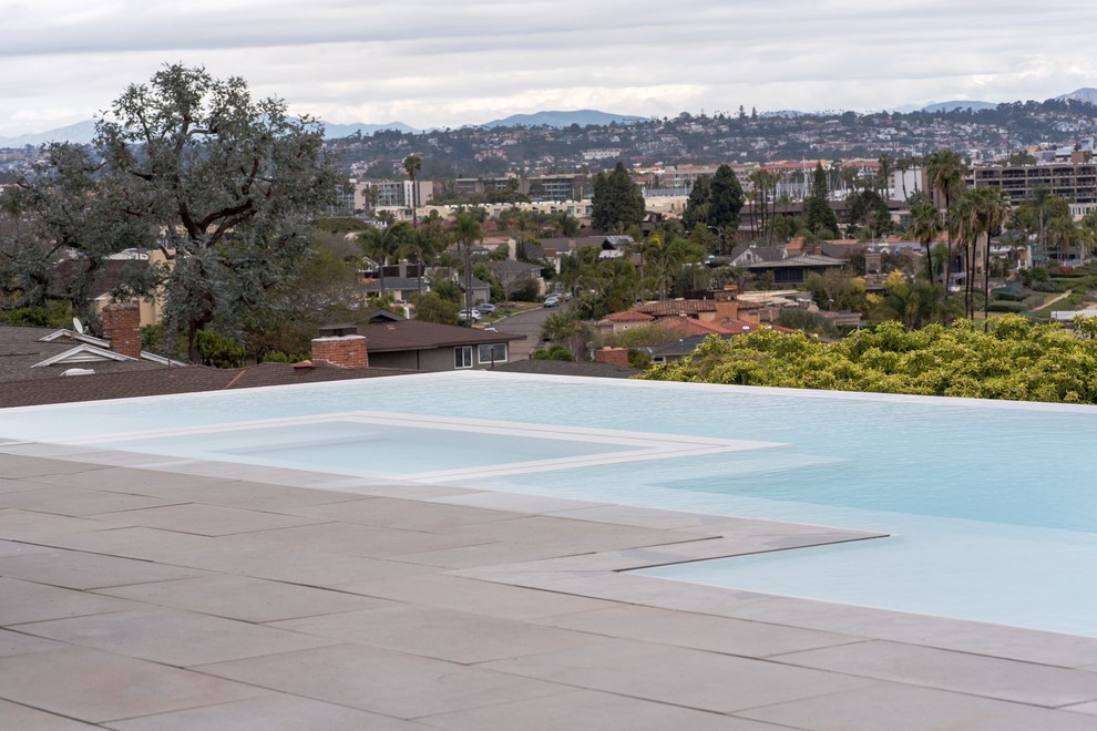 Aménagement d'une grande piscine à débordement et arrière contemporaine rectangle avec des pavés en béton.