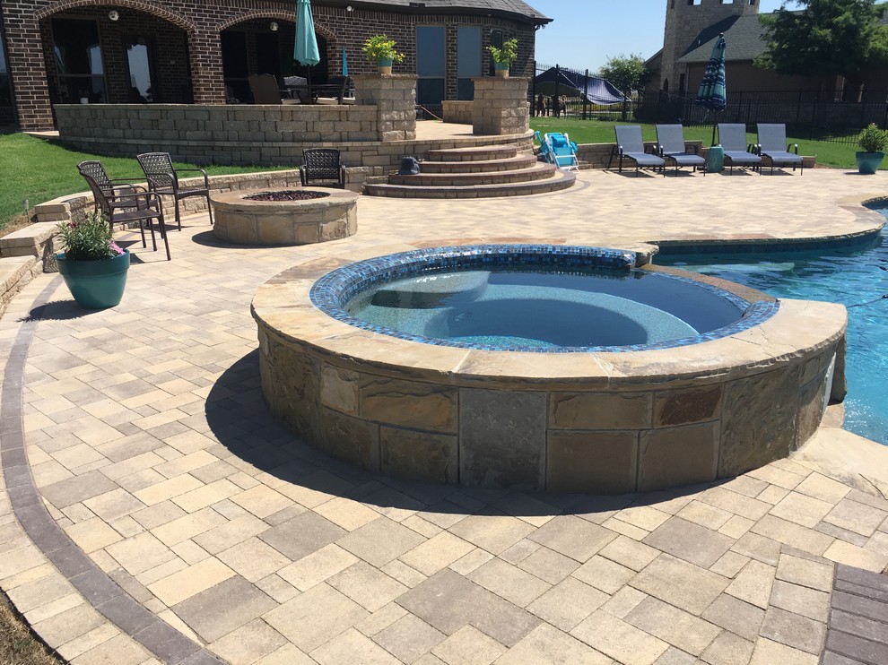 Ejemplo de piscinas y jacuzzis de estilo americano extra grandes a medida en patio trasero con adoquines de piedra natural