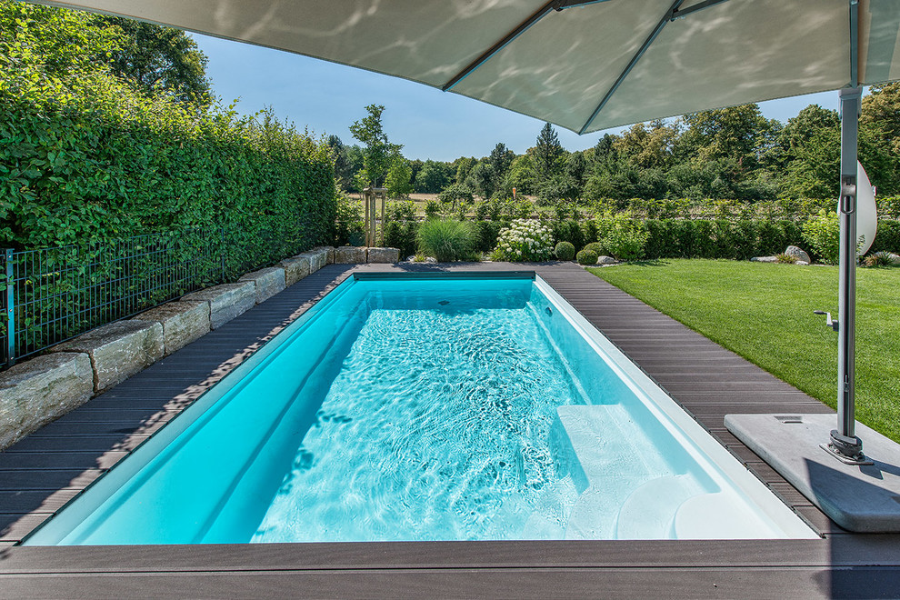 Immagine di una piscina monocorsia design rettangolare dietro casa e di medie dimensioni con pedane
