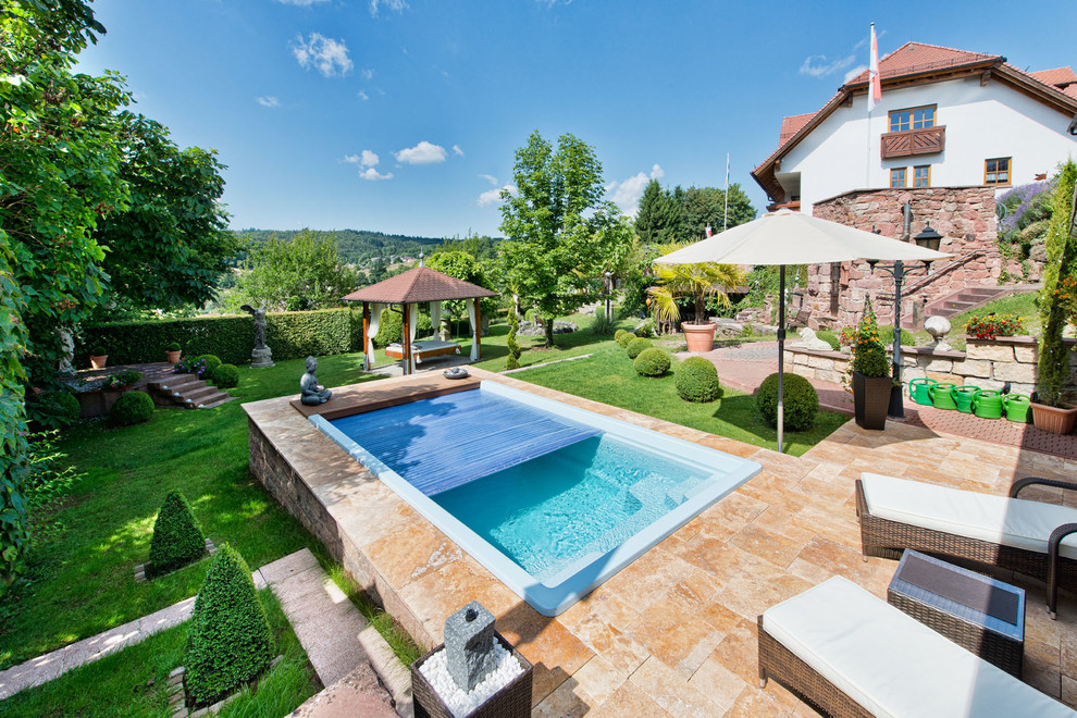 Diseño de piscina alargada de estilo zen pequeña rectangular en patio trasero con adoquines de piedra natural