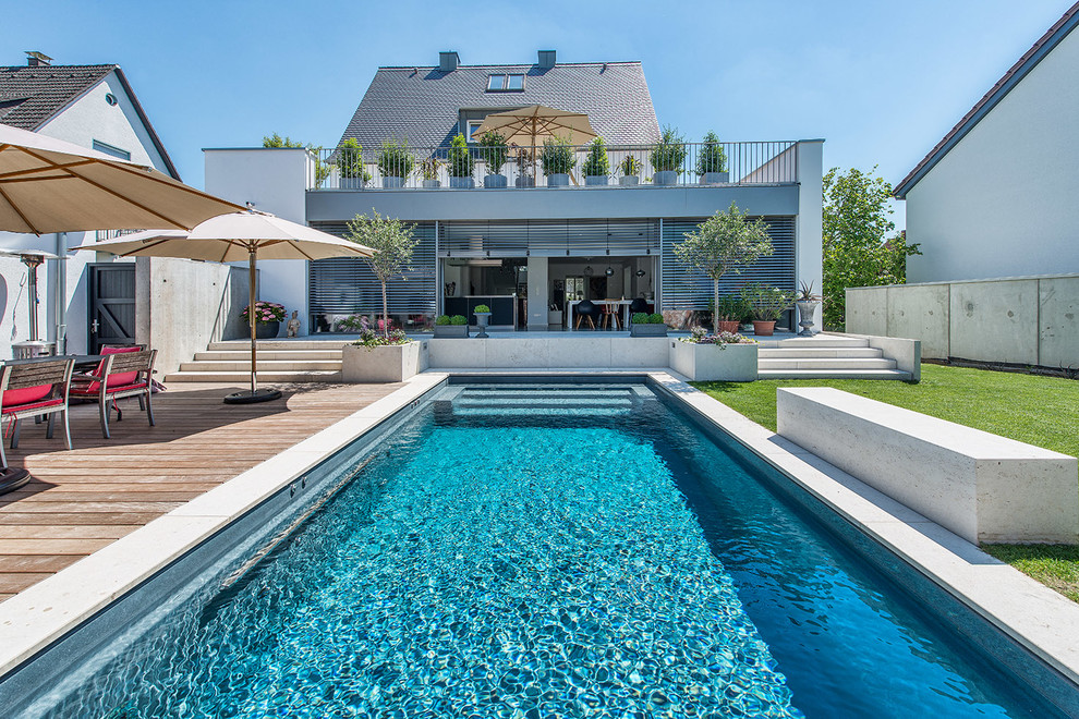 Источник вдохновения для домашнего уюта: большой прямоугольный, спортивный бассейн на заднем дворе в современном стиле с настилом