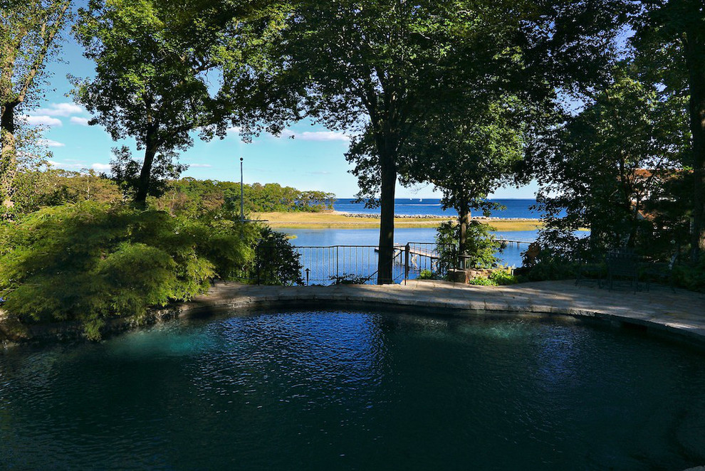 Foto de piscina natural de estilo americano grande a medida en patio trasero con adoquines de hormigón