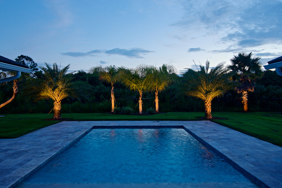 Foto di una grande piscina monocorsia stile marino rettangolare dietro casa con pavimentazioni in pietra naturale