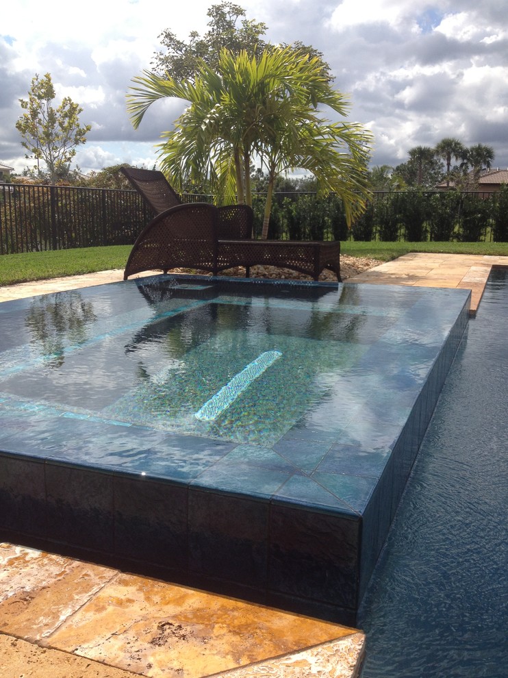 Diseño de piscinas y jacuzzis infinitos minimalistas en patio trasero con adoquines de piedra natural
