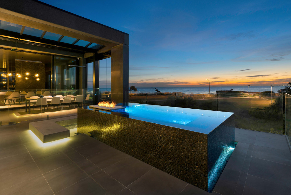 Idee per una grande piscina a sfioro infinito moderna rettangolare dietro casa con paesaggistica bordo piscina e piastrelle