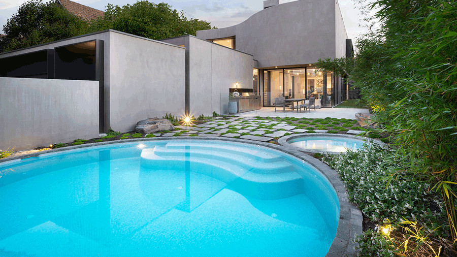 Ispirazione per una grande piscina minimalista rotonda davanti casa con paesaggistica bordo piscina e graniglia di granito