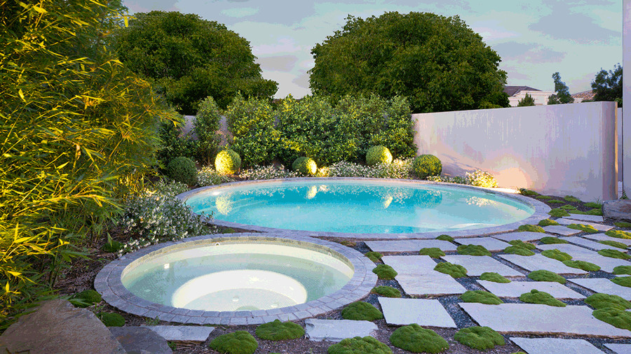 Modern inredning av en stor rund pool framför huset, med granitkomposit