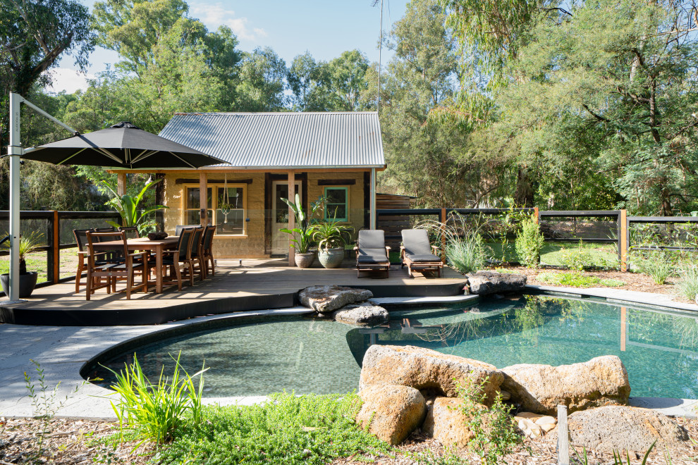 Ejemplo de casa de la piscina y piscina natural de estilo americano grande a medida en patio trasero con adoquines de piedra natural