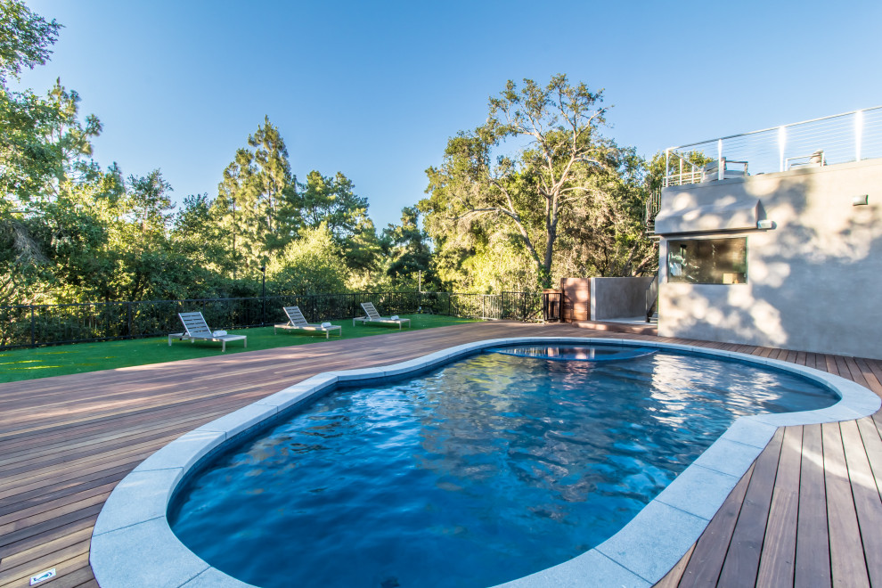 Diseño de piscinas y jacuzzis actuales de tamaño medio tipo riñón en patio trasero con entablado