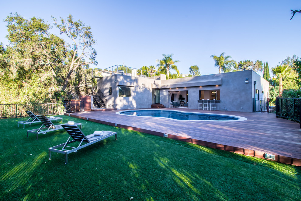 Aménagement d'une piscine arrière contemporaine en forme de haricot de taille moyenne avec un bain bouillonnant et une terrasse en bois.