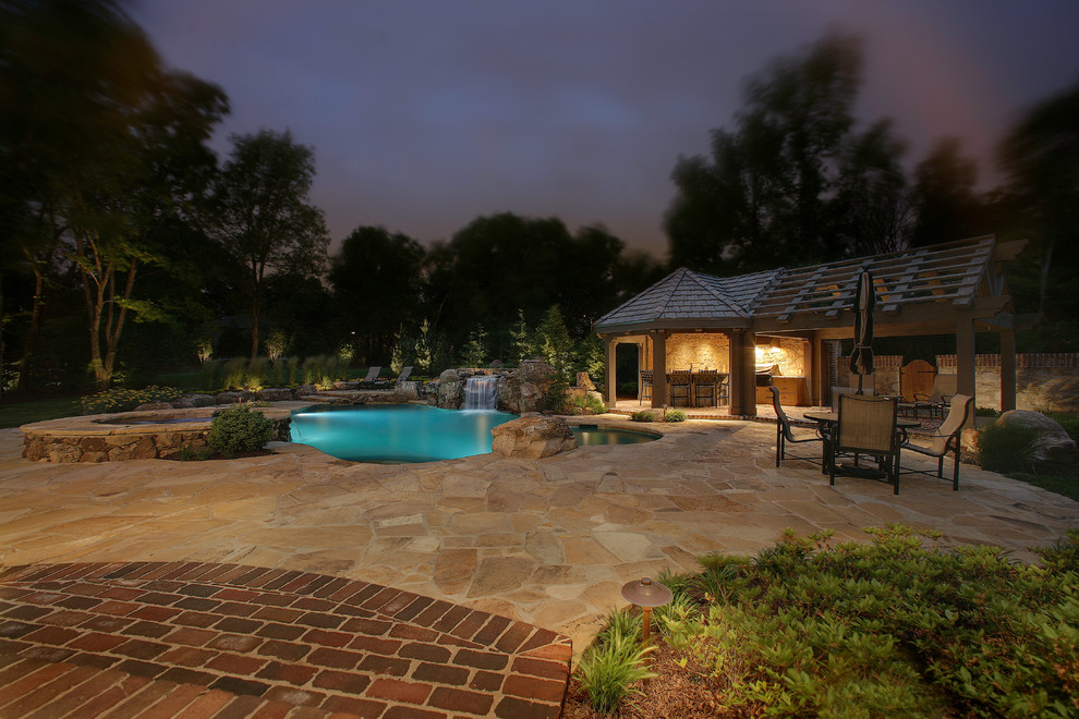 Foto di una grande piscina naturale stile americano personalizzata in cortile con una vasca idromassaggio e pavimentazioni in pietra naturale