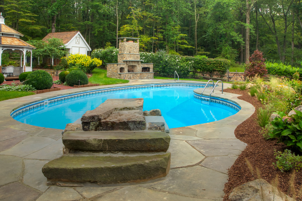 Idées déco pour une grande piscine arrière classique en forme de haricot avec des pavés en pierre naturelle.