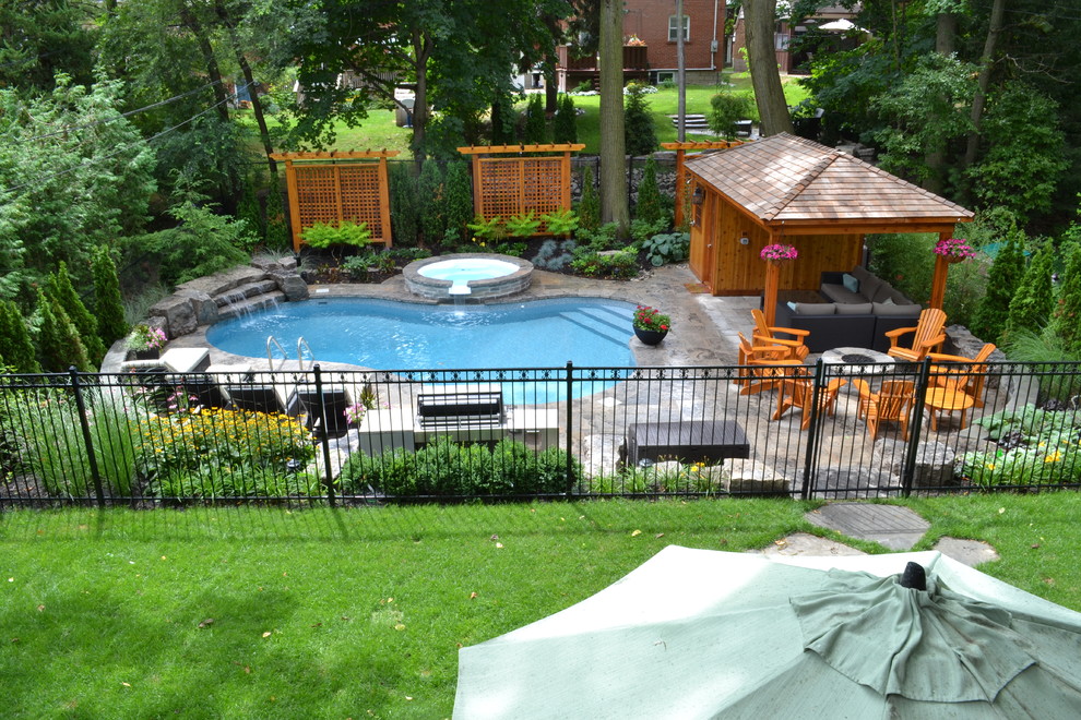 Foto di una piscina tropicale personalizzata di medie dimensioni e dietro casa con una vasca idromassaggio e pavimentazioni in pietra naturale