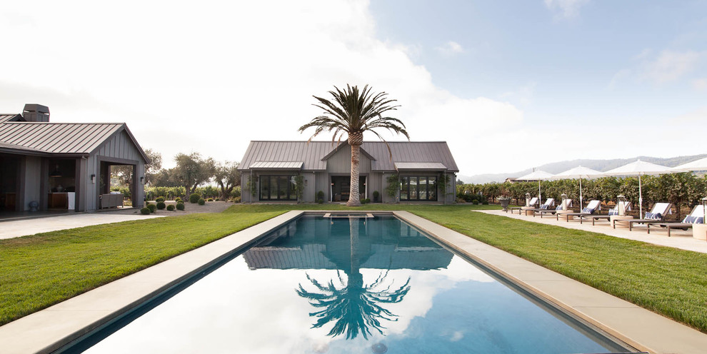 Foto de casa de la piscina y piscina alargada campestre extra grande rectangular en patio trasero con losas de hormigón