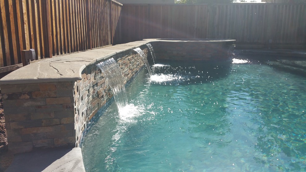 Modelo de piscinas y jacuzzis clásicos de tamaño medio tipo riñón en patio trasero con suelo de hormigón estampado