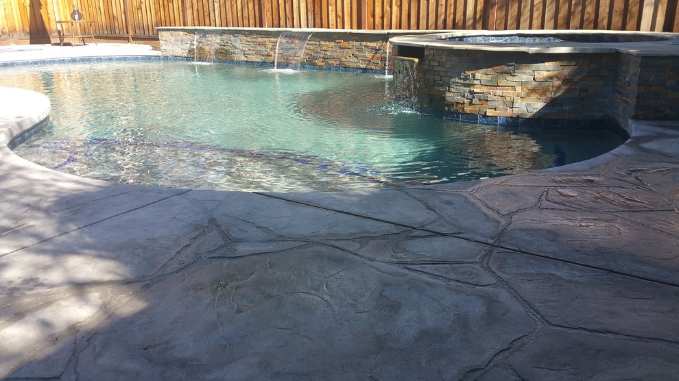 Aménagement d'une piscine arrière classique en forme de haricot de taille moyenne avec du béton estampé et un bain bouillonnant.