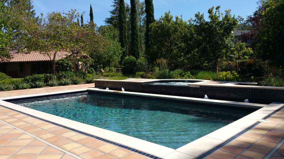 Esempio di una piscina monocorsia mediterranea rettangolare di medie dimensioni e dietro casa con fontane e piastrelle