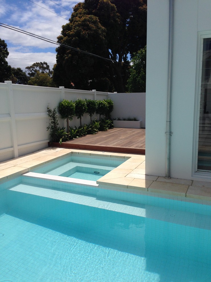Cette photo montre une piscine intérieure moderne en L de taille moyenne avec un bain bouillonnant et des pavés en pierre naturelle.