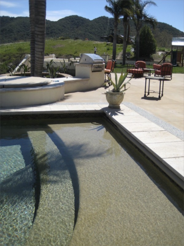 На фото: большой прямоугольный бассейн-инфинити на заднем дворе в стиле фьюжн с водной горкой и мощением тротуарной плиткой с
