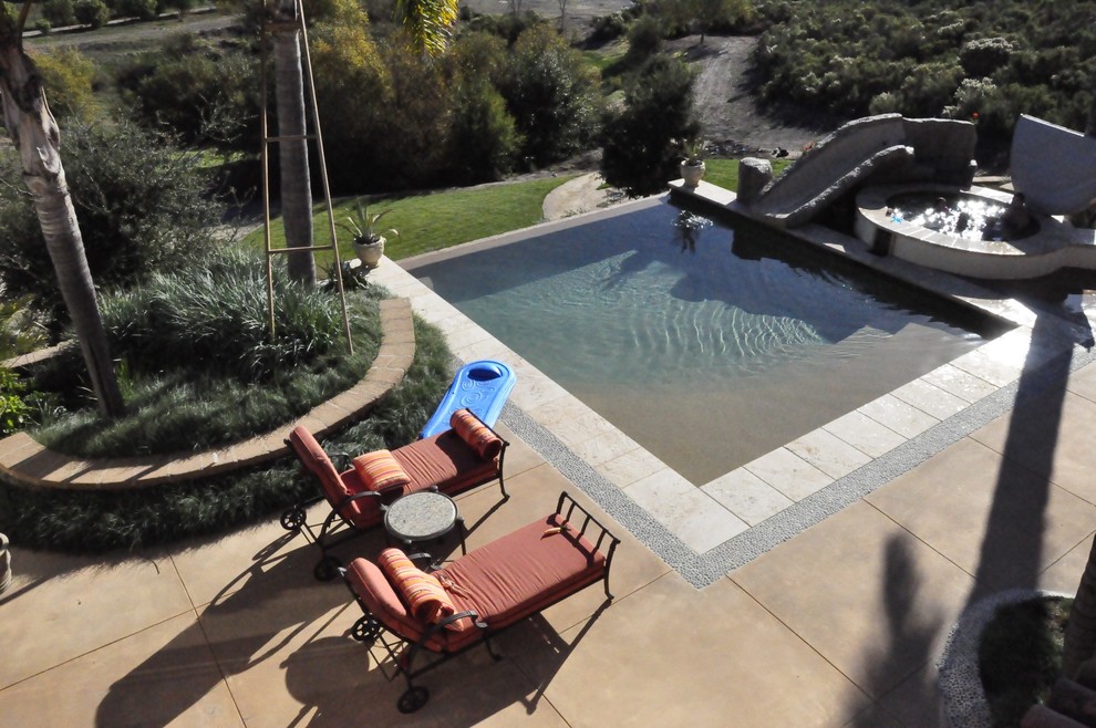 На фото: большой прямоугольный бассейн-инфинити на заднем дворе в современном стиле с водной горкой и мощением тротуарной плиткой с