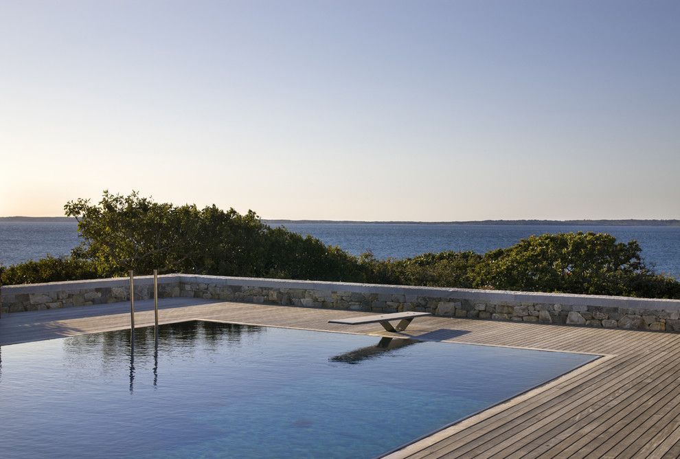 Idée de décoration pour une piscine à débordement marine rectangle avec une terrasse en bois.