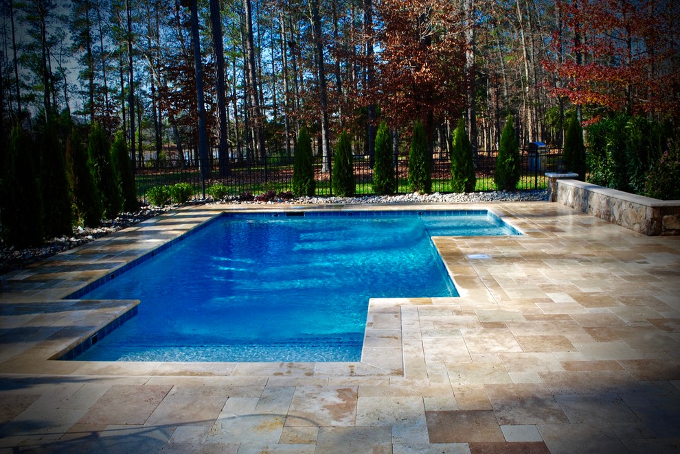 Modelo de piscina natural mediterránea pequeña en forma de L en patio trasero con adoquines de piedra natural
