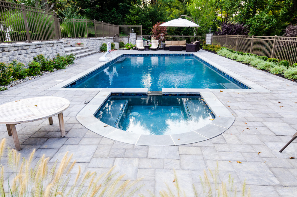 Inspiration for a large modern back rectangular natural hot tub in New York with brick paving.
