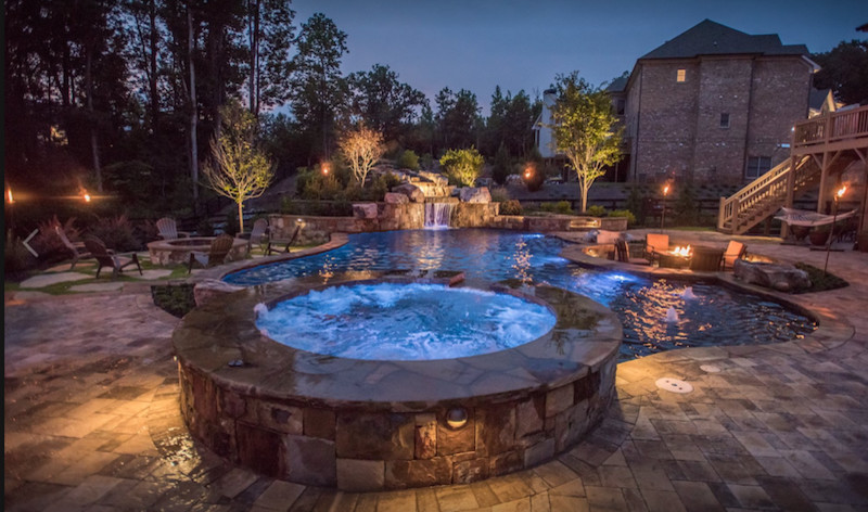 Imagen de piscinas y jacuzzis naturales clásicos renovados grandes a medida en patio trasero con adoquines de piedra natural