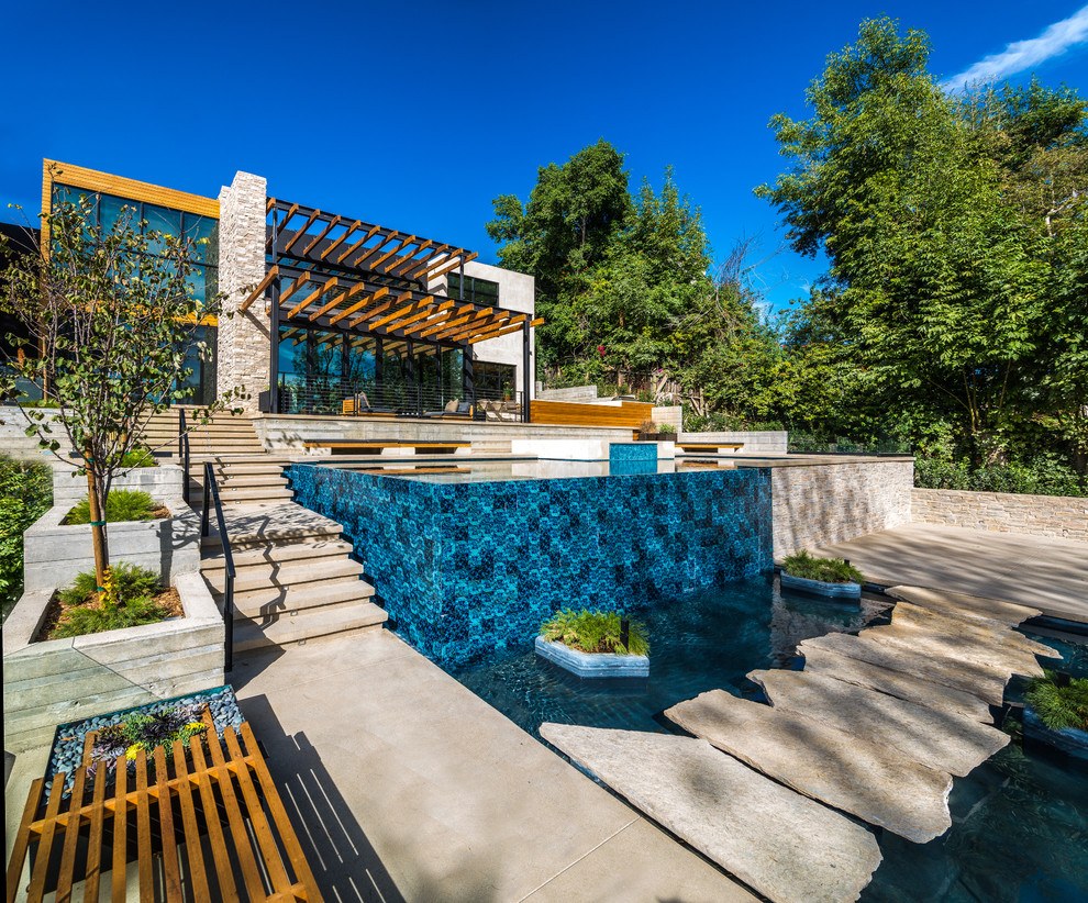 Modelo de piscina infinita contemporánea de tamaño medio rectangular en patio trasero con losas de hormigón