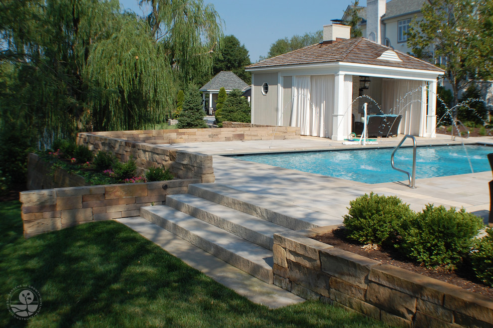 Foto de casa de la piscina y piscina alargada actual grande rectangular en patio trasero con suelo de baldosas