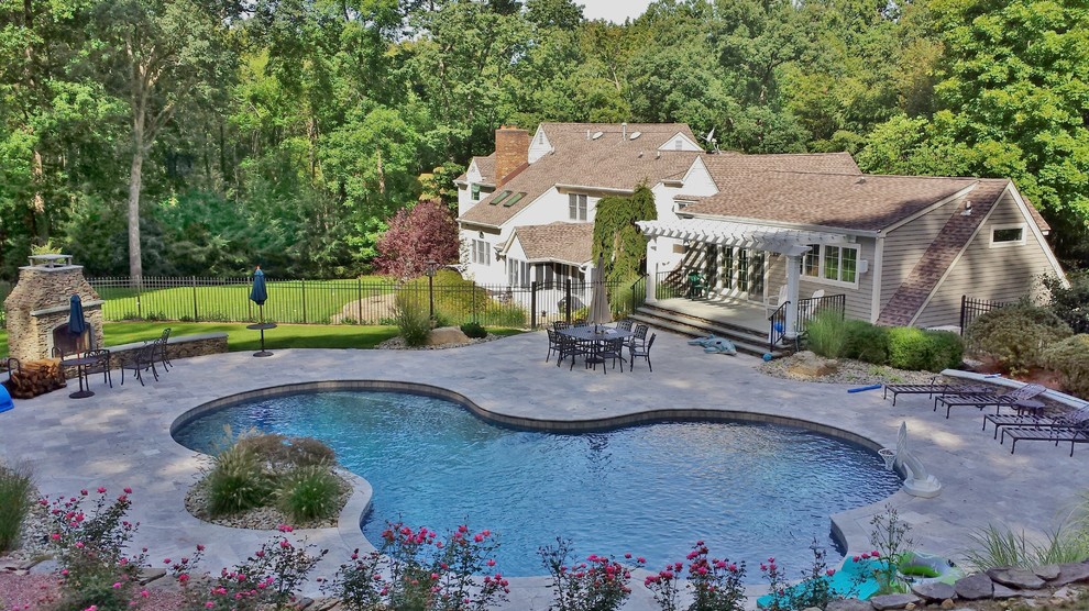 Ispirazione per un'ampia piscina naturale classica personalizzata dietro casa con pavimentazioni in pietra naturale e una dépendance a bordo piscina