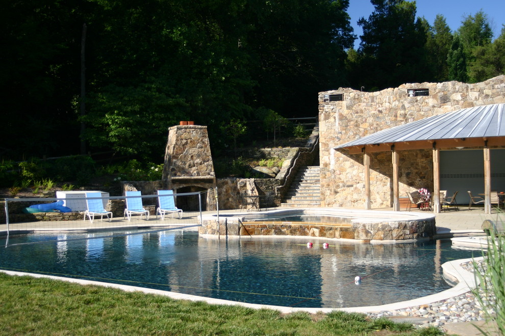 На фото: огромный естественный бассейн произвольной формы на заднем дворе в стиле фьюжн с домиком у бассейна и мощением тротуарной плиткой с