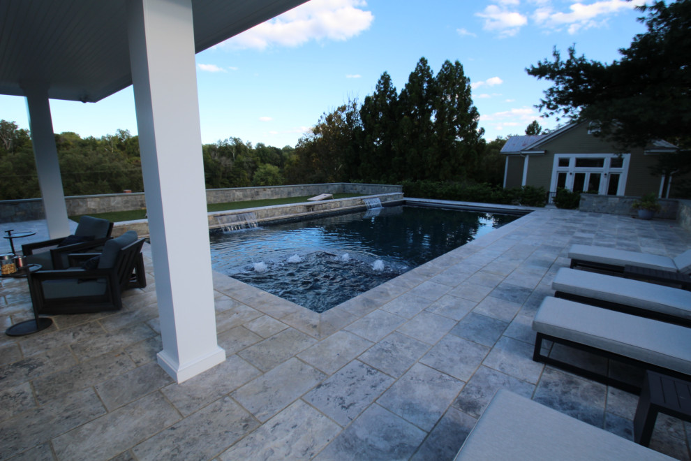 Cette photo montre un grand Abris de piscine et pool houses arrière tendance rectangle avec des pavés en pierre naturelle.