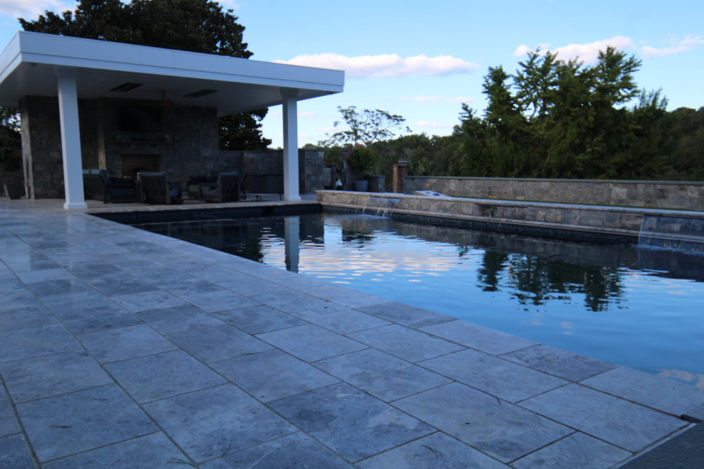 Exemple d'un grand Abris de piscine et pool houses arrière tendance rectangle avec des pavés en pierre naturelle.