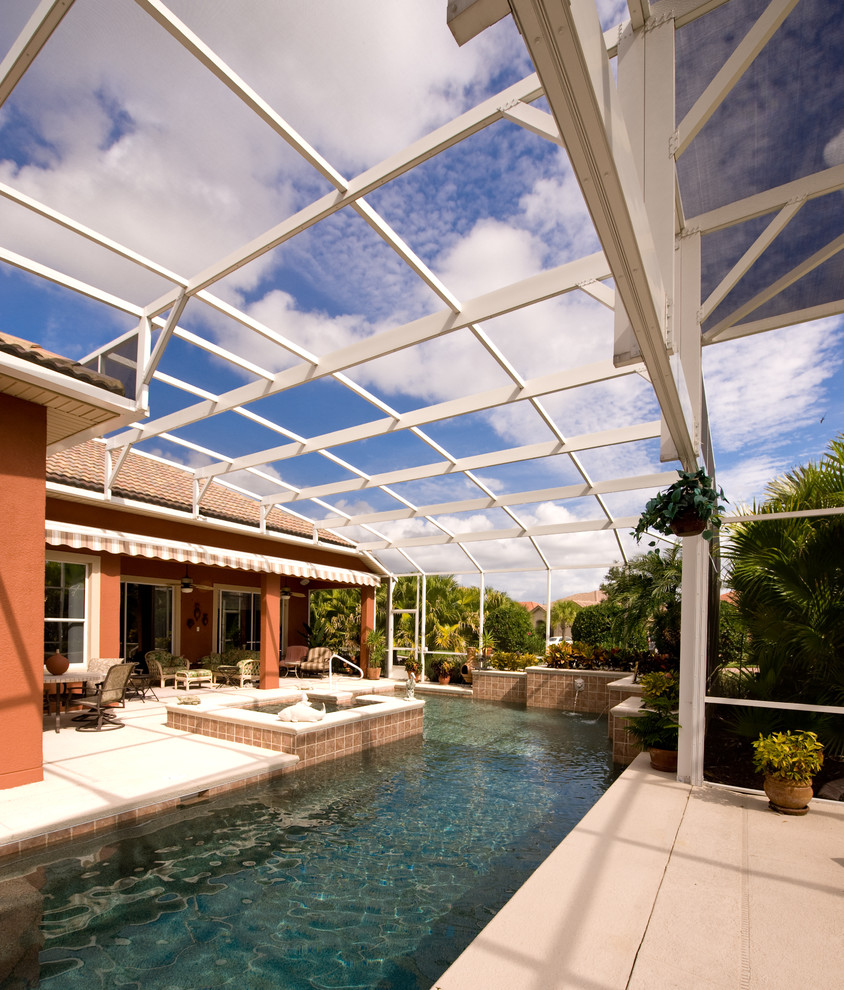 Foto de piscinas y jacuzzis alargados tradicionales grandes en forma de L en patio trasero con losas de hormigón