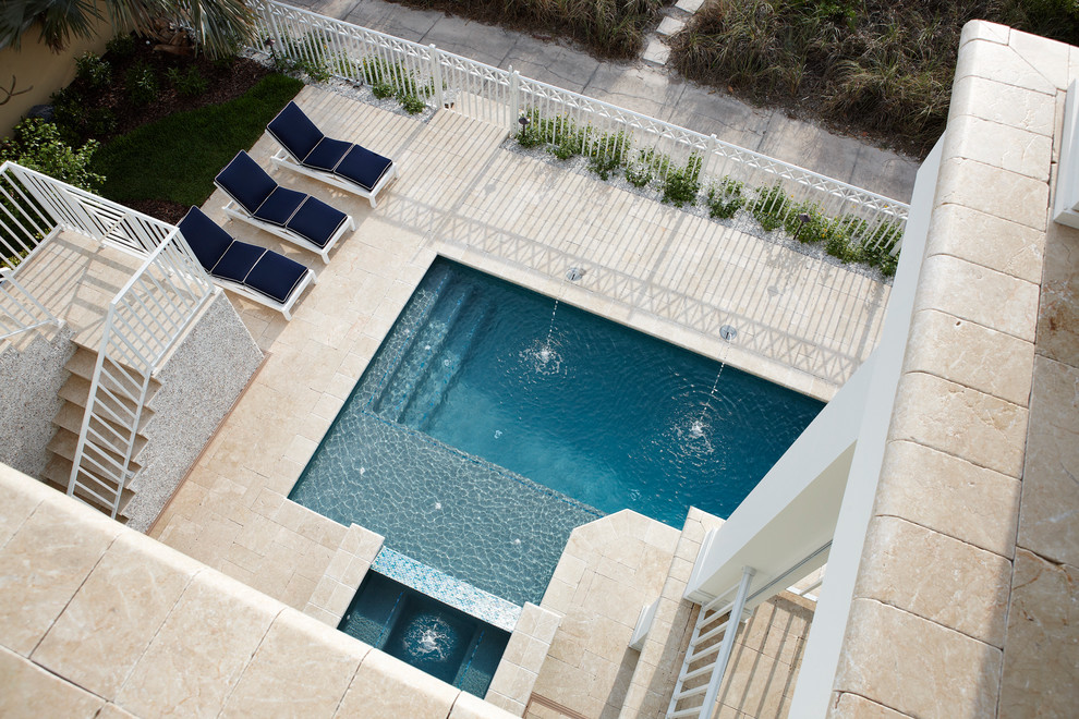Photo of a large contemporary back rectangular lengths swimming pool in Tampa with a water feature and natural stone paving.