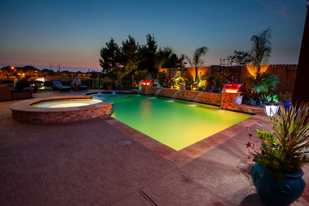 Immagine di una piscina design rettangolare di medie dimensioni e dietro casa con fontane