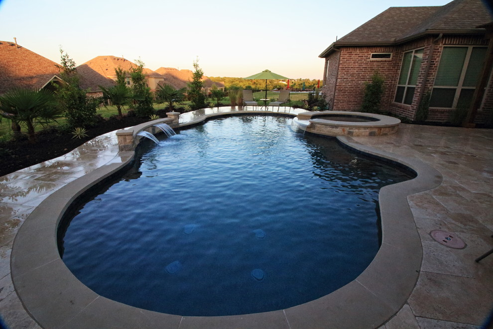 Modelo de piscina natural tradicional renovada de tamaño medio tipo riñón en patio trasero con adoquines de piedra natural