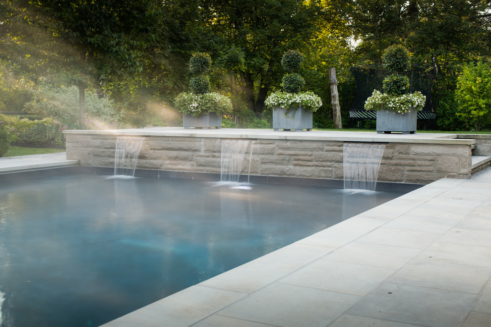 Modelo de casa de la piscina y piscina tradicional renovada grande rectangular en patio trasero con adoquines de piedra natural