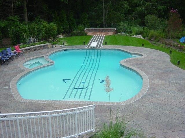 Foto de piscinas y jacuzzis contemporáneos grandes a medida en patio trasero con adoquines de piedra natural