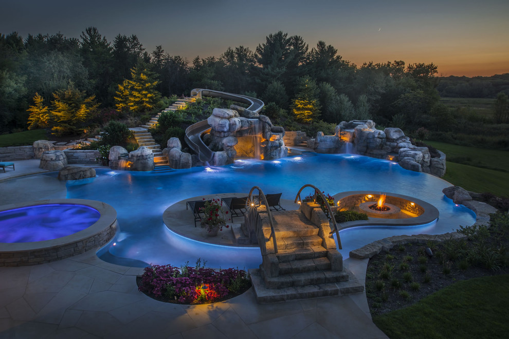Immagine di un'ampia piscina a sfioro infinito personalizzata dietro casa con una vasca idromassaggio e pavimentazioni in pietra naturale