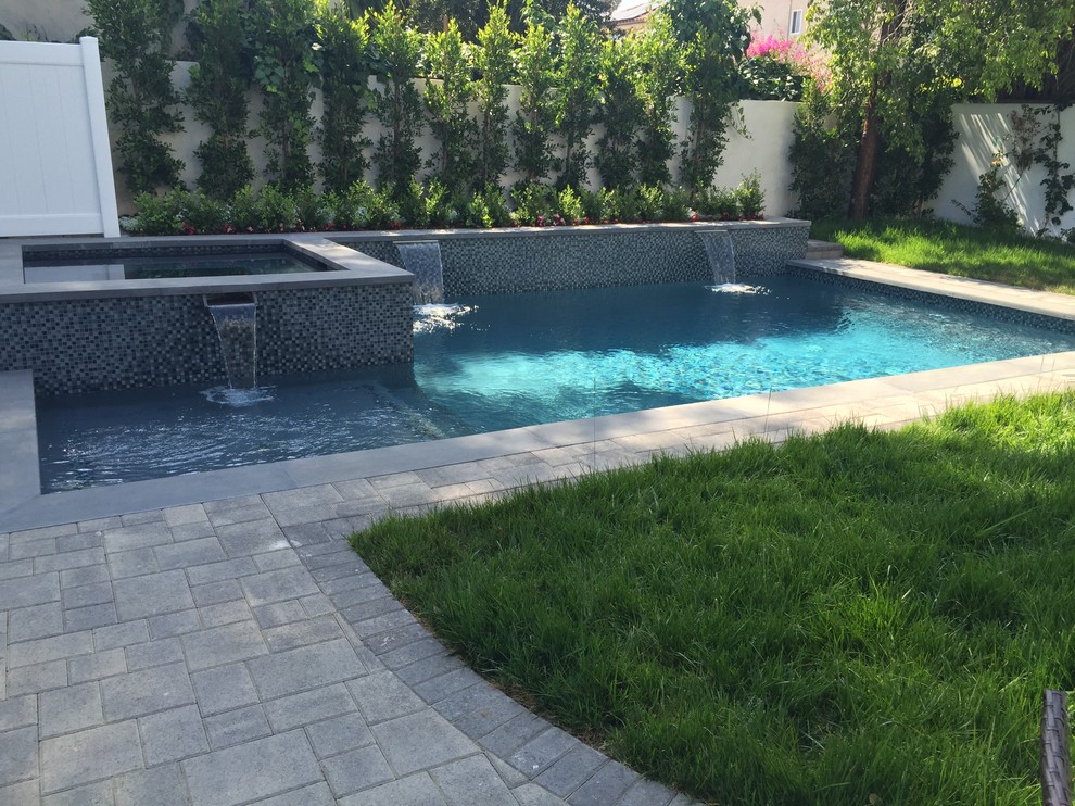 Esempio di una piscina naturale mediterranea rettangolare di medie dimensioni e dietro casa con pavimentazioni in cemento e fontane