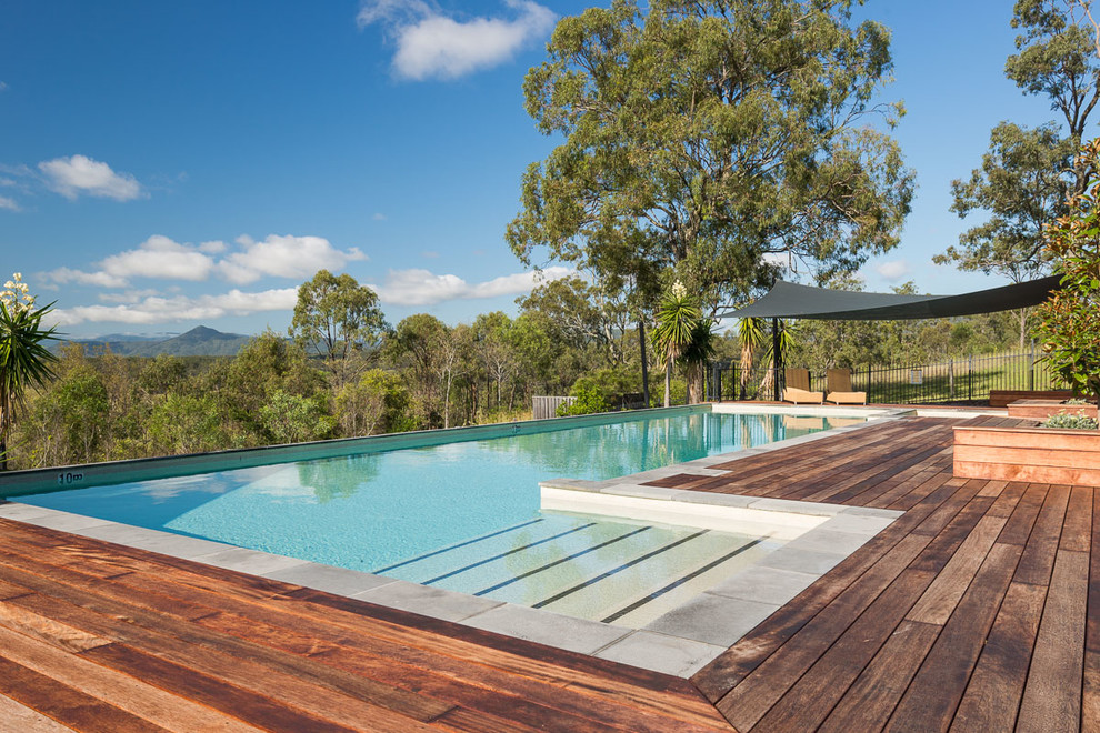 Imagen de piscina alargada campestre grande a medida en patio trasero con entablado